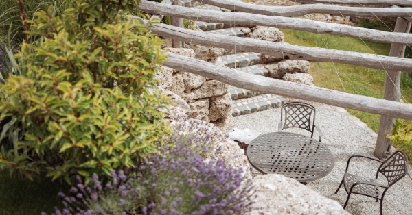 Sitzplatz mit einer Mauer aus Nagefluh, Natursteintreppe Granit und einer Pergola aus Holz